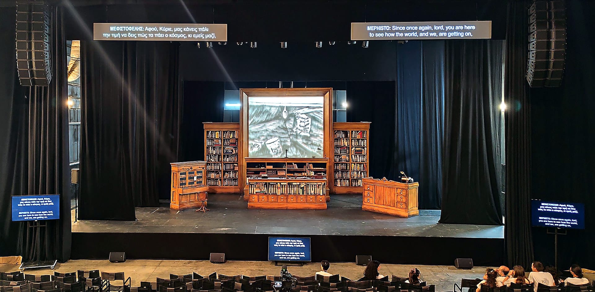 Surtitle screens over a stage set at Pireos 260